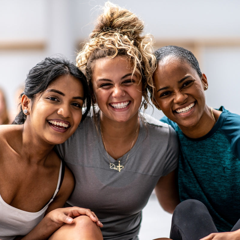 Three women smiling and posing together in a casual setting